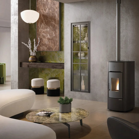 Ambientebild: Extraflame Pelletofen ANGELICA PLUS in Schwarz, in modernem Wohnzimmer neben Fenster, Regal, Hocker und Tisch mit Pflanze | Klimaworld.com
