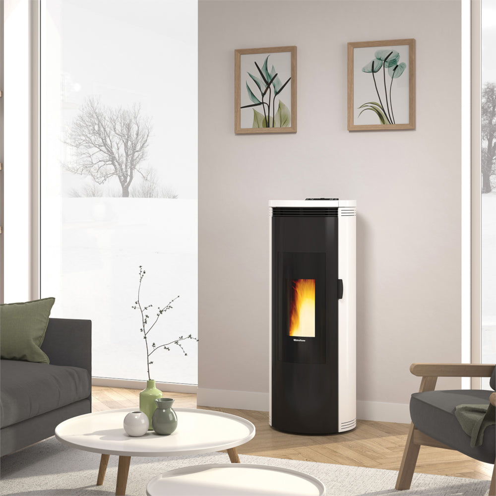 Ambientebild: Extraflame Pelletofen AMIKA EVO in Schwarz-Weiss mit abgerundeten Seiten, Sichtfenster und Flamme, im hellen Wohnzimmer mit Sofa und Tisch | Klimaworld.com