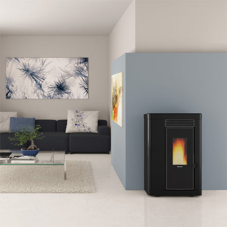 Ambientebild: schmaler Extraflame Pelletofen ANNABELLA AD EVO in Schwarz; im Wohnzimmer vor blauer Wand, Sofa, Bild und Glastisch | Klimaworld.com
