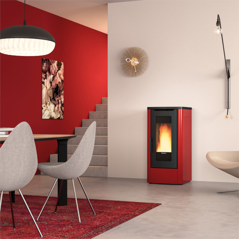 Ambientebild: Extraflame kanalisierter Pelletofen DAHIANA PLUS 5.0 EVO in Bordeaux, im Wohnzimmer neben Treppe roter Wand Tisch Stuehlen | Klimaworld.com