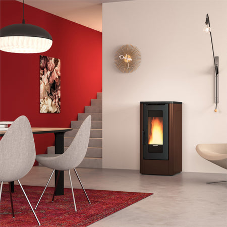Ambientebild: Extraflame kanalisierter Pelletofen DAHIANA PLUS 5.0 EVO in Bronze, im Wohnzimmer neben Treppe roter Wand Tisch Stuehlen | Klimaworld.com