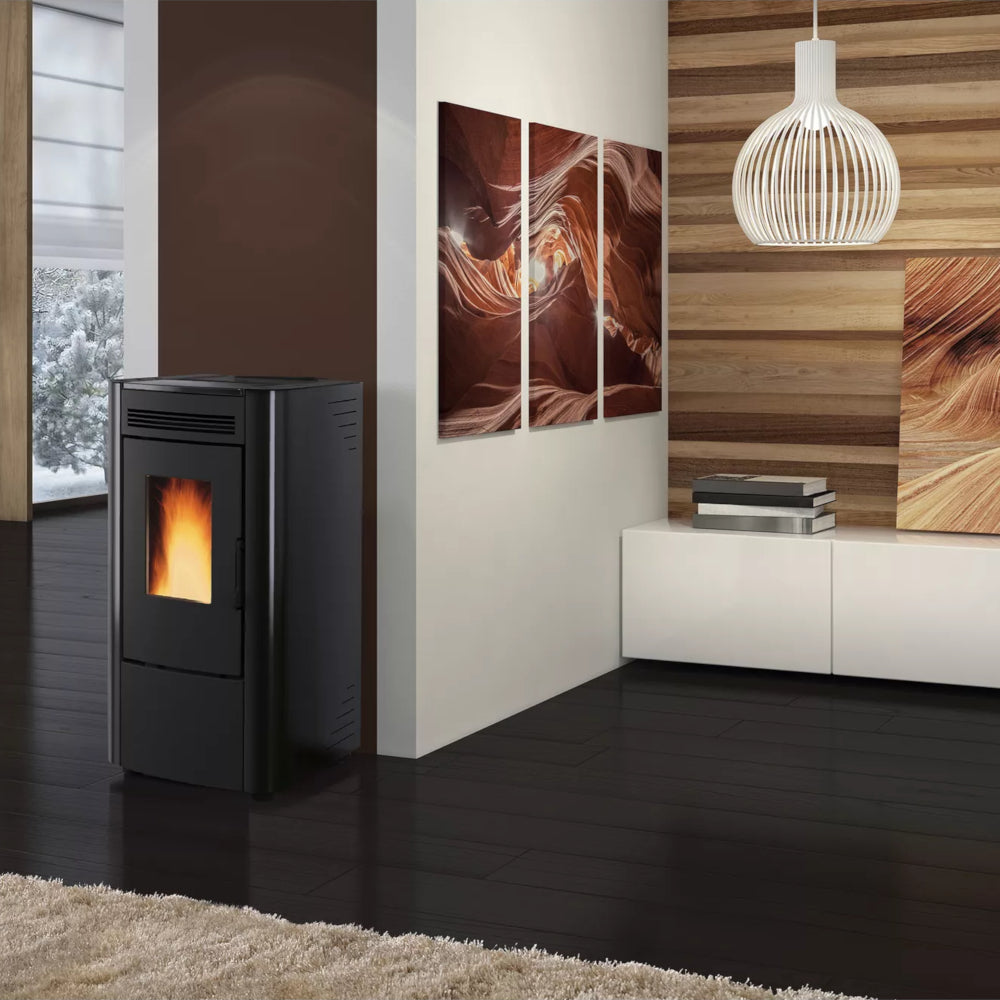 Ambientebild: Extraflame beluefteter Pelletofen KETTY 5.0 in Schwarz mit sichtbarer Flamme im modernem Wohnraum neben Kunstwerk | Klimaworld.com