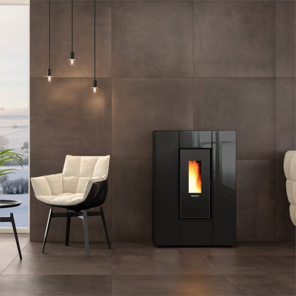 Ambientebild: schlanker Extraflame kanalisierter Pelletofen MARILENA PLUS CRYSTAL 5.0.16 in Schwarzer Glasfront vor dunkler Wand im Wohnraum mit Flamme | Klimaworld.com