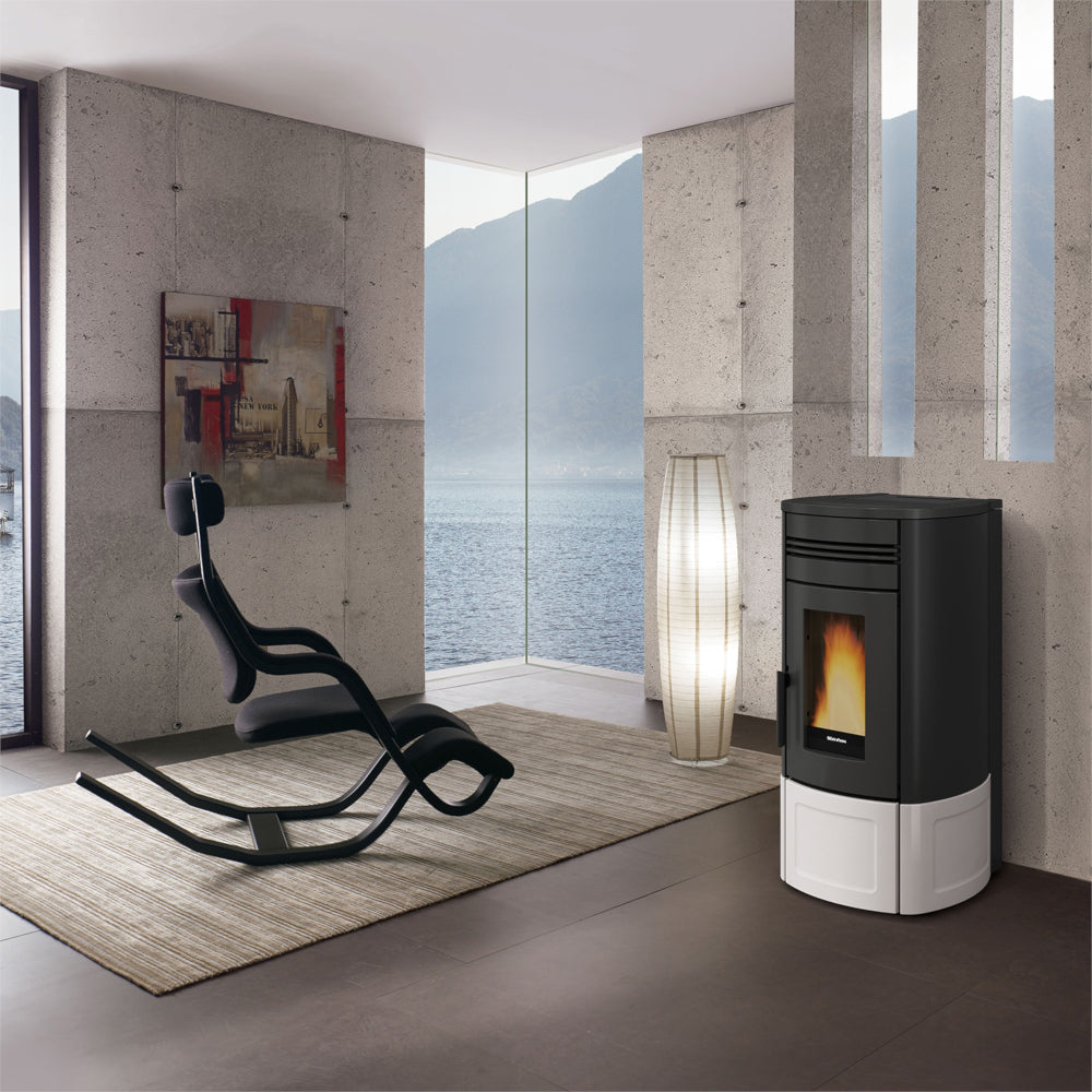 Ambientebild: Extraflame beluefteter Pelletofen NORIS Lux in schwarz-weiß vor Betonwand, Flamme sichtbar, moderner Wohnraum | Klimaworld.com