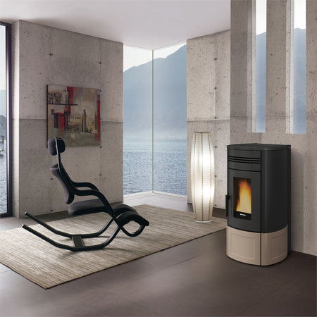 Ambientebild: Extraflame beluefteter Pelletofen NORIS Lux in schwarz-bronze vor Betonwand, Flamme sichtbar, moderner Wohnraum | Klimaworld.com