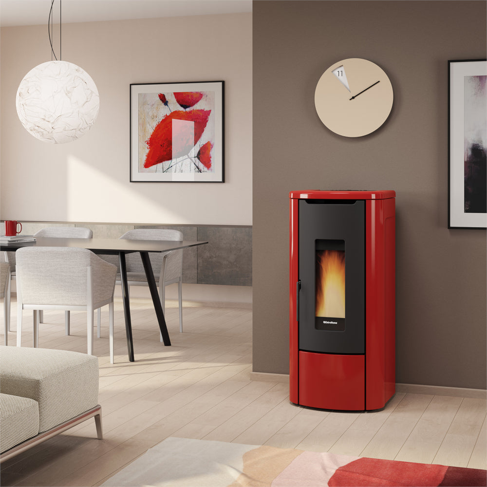 Ambientebild: Extraflame wasserfuehrender Pelletofen ROSANNA IDRO 5.0 in Bordeaux; im Wohnzimmer an Wand neben Tisch, Bild und Uhr | Klimaworld.com
