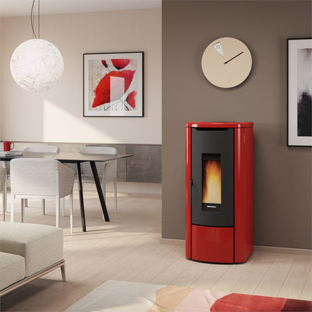 Ambientebild: Extraflame wasserfuehrender Pelletofen ROSANNA IDRO 5.0 in Bordeaux; im Wohnzimmer an Wand neben Tisch, Bild und Uhr | Klimaworld.com