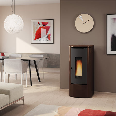 Ambientebild: Extraflame wasserfuehrender Pelletofen ROSANNA IDRO 5.0 in Bronze; im Wohnzimmer an Wand neben Tisch, Bild und Uhr | Klimaworld.com