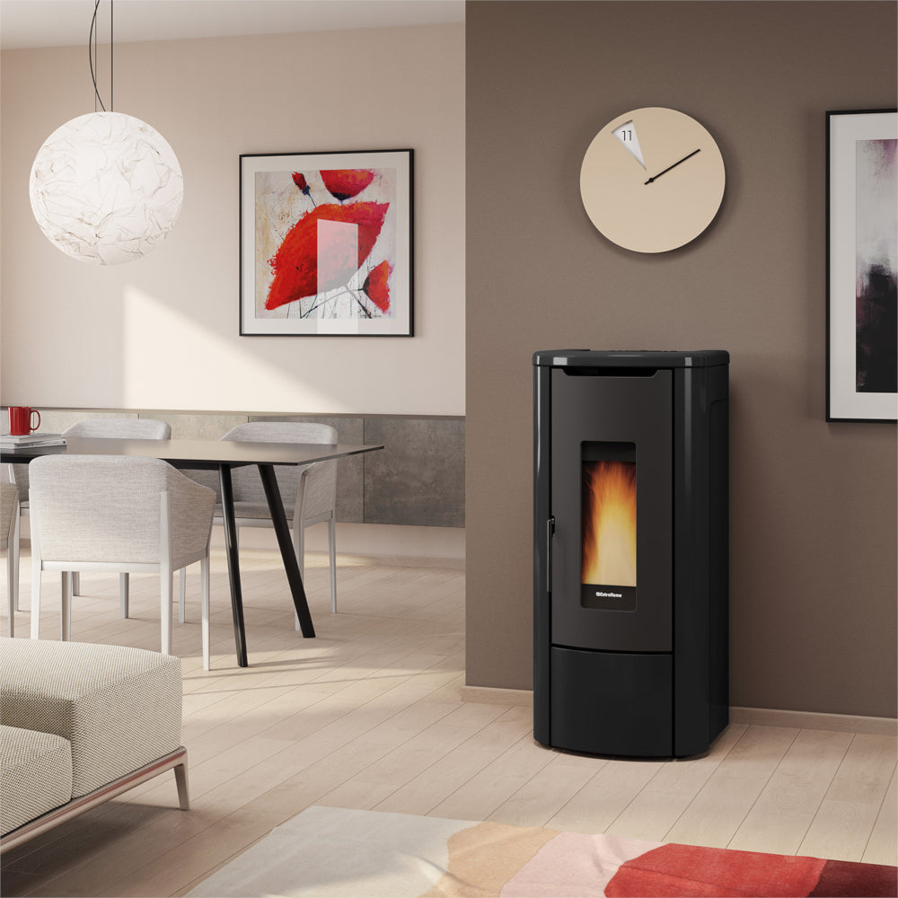 Ambientebild: Extraflame wasserfuehrender Pelletofen ROSANNA IDRO 5.0 in Schwarz; im Wohnzimmer an Wand neben Tisch, Bild und Uhr | Klimaworld.com
