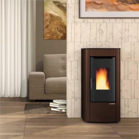 abgerundeter Extraflame beluefteter Pelletofen SABRY 5.0 EVO in Bronze vor heller Steinwand mit Bild, Sessel und Vorhang | Klimaworld.com
