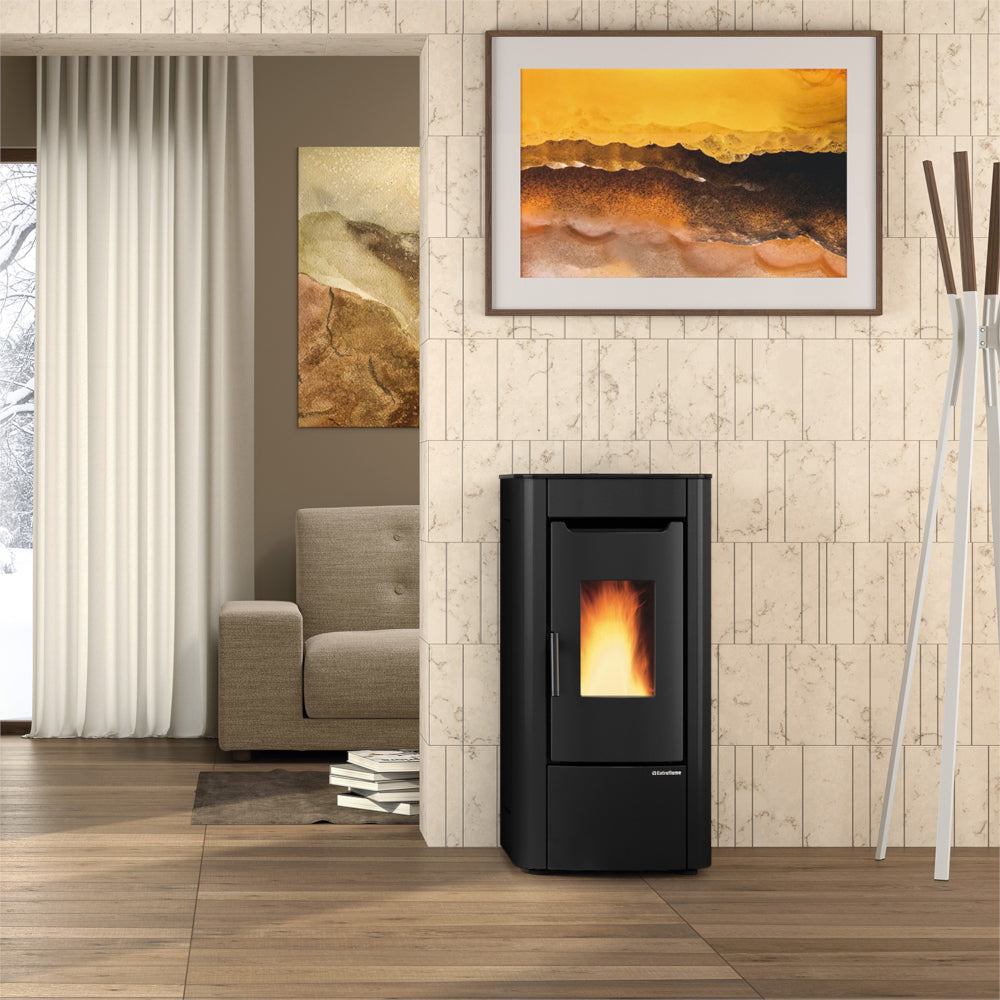 abgerundeter Extraflame beluefteter Pelletofen SABRY 5.0 EVO vor heller Steinwand mit Bild, Sessel und Vorhang | Klimaworld.com
