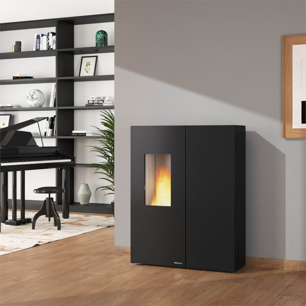 Ambientebild: Extraflame Pelletofen SHARON PLUS STEEL schwarz vor Wand, Flamme sichtbar, Regal, Klavier und Pflanze im Raum | Klimaworld.com