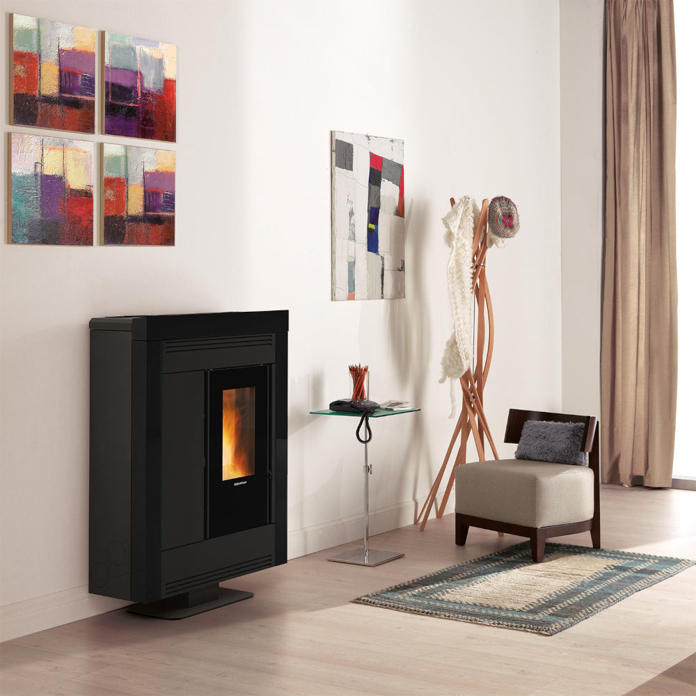 Ambientebild: schmaler Extraflame kanalisierter Pelletofen SOUVENIR PLUS STEEL 5.0 in Schwarz; im Wohnraum mit Sessel, Teppich und Wandbildern| Klimaworld.com