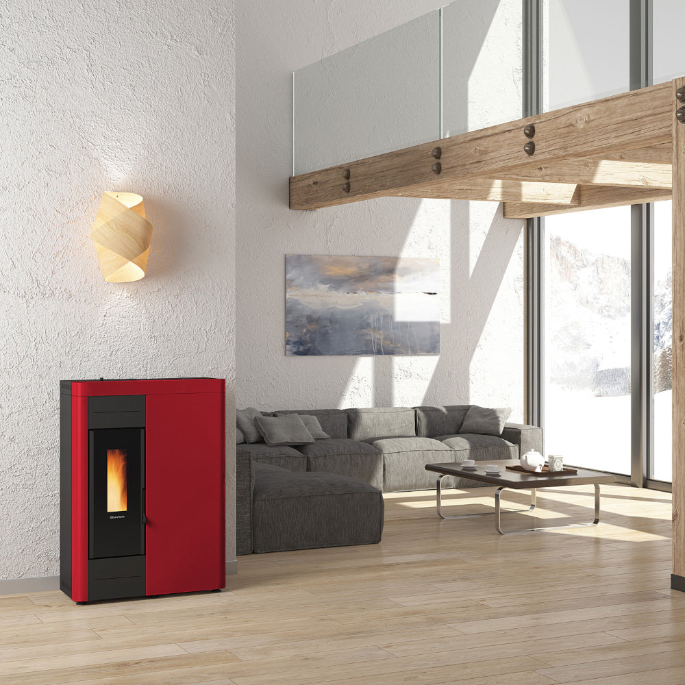 Ambientebild: schmaler Extraflame Pelletofen VIRNA IDRO.16 in Rot mit schwarzer Scheibe Flamme sichtbar im offenem Wohnraum Sofa | Klimaworld.com