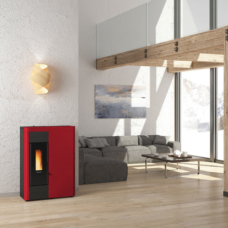 Ambientebild: schmaler Extraflame Pelletofen VIRNA IDRO.16 in Rot mit schwarzer Scheibe Flamme sichtbar im offenem Wohnraum Sofa | Klimaworld.com