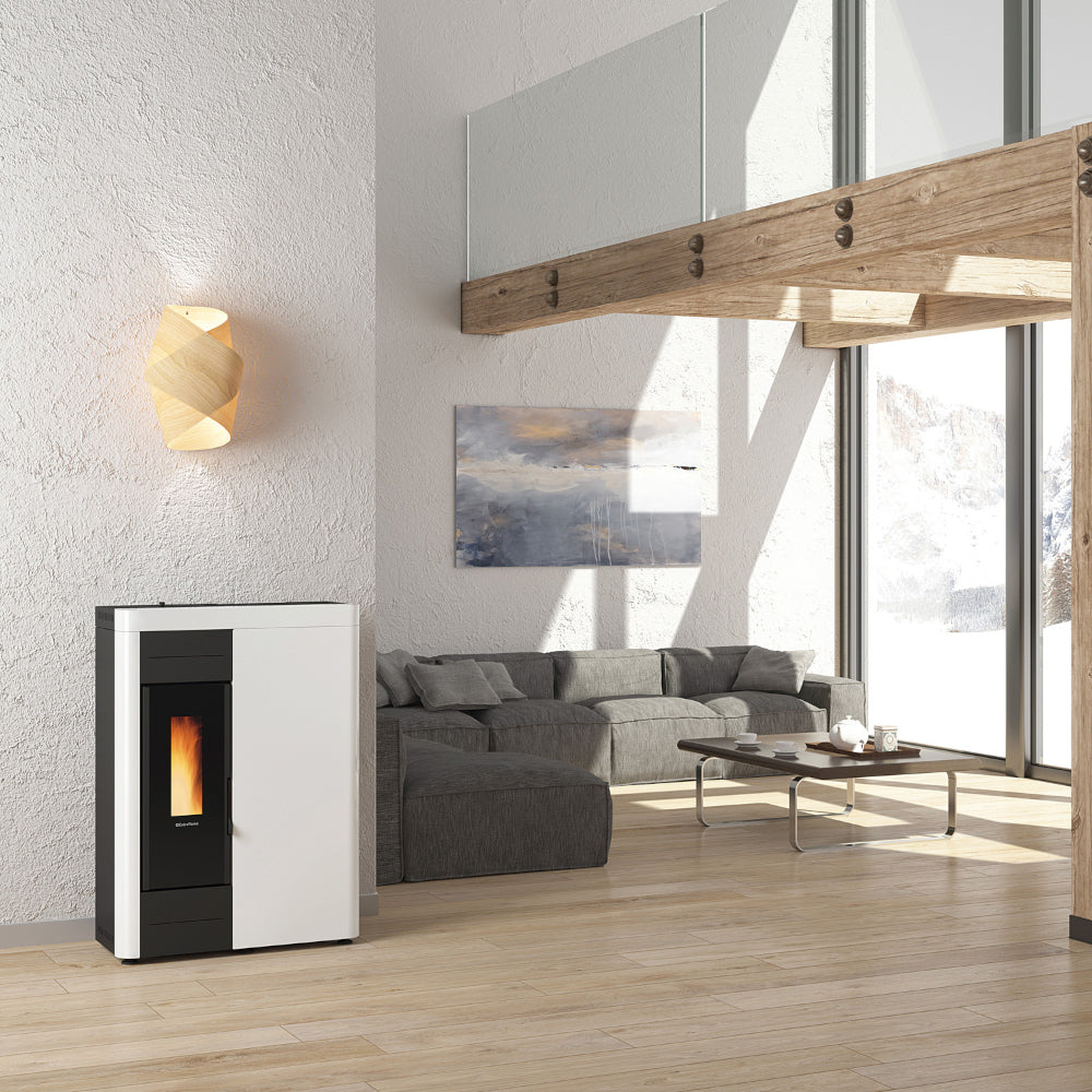 Ambientebild: schmaler Extraflame Pelletofen VIRNA IDRO.16 in Weiss mit schwarzer Scheibe Flamme sichtbar im offenem Wohnraum Sofa | Klimaworld.com