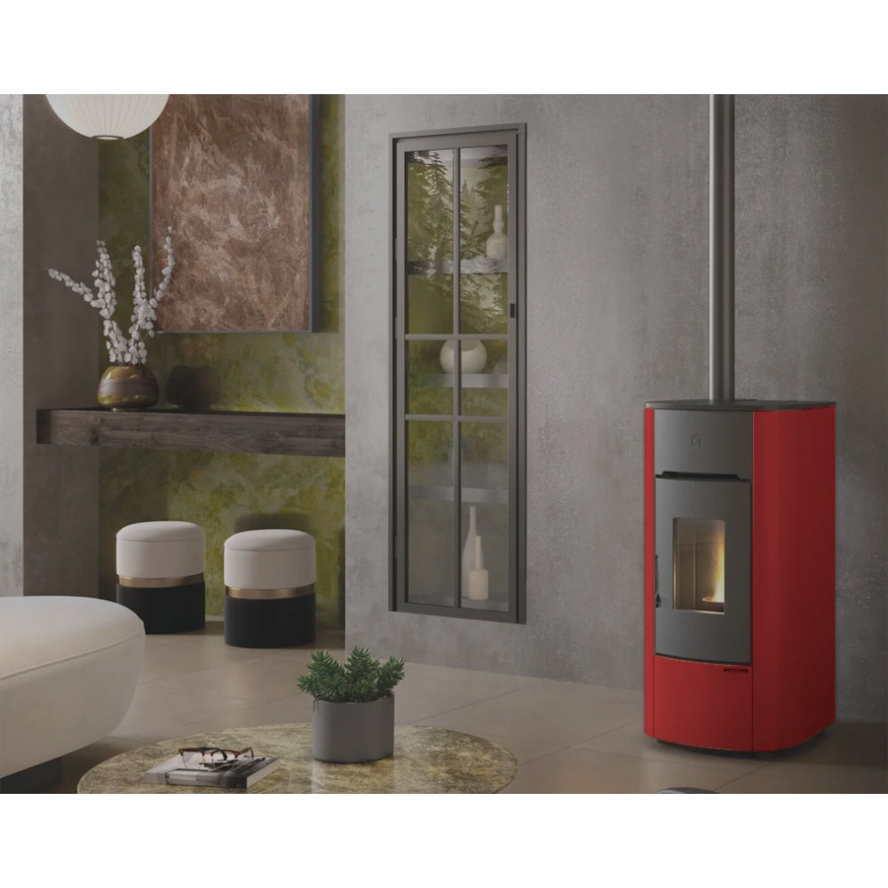 Ambientebild: Extraflame Pelletofen ANGELICA PLUS in Bordeaux, in modernem Wohnzimmer neben Fenster, Regal, Hocker und Tisch mit Pflanze | Klimaworld.com
