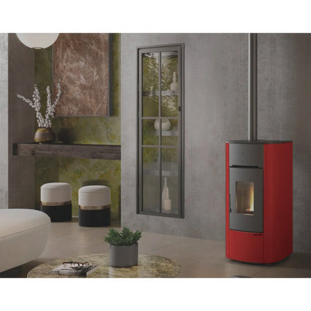 Ambientebild: Extraflame Pelletofen ANGELICA PLUS in Bordeaux, in modernem Wohnzimmer neben Fenster, Regal, Hocker und Tisch mit Pflanze | Klimaworld.com
