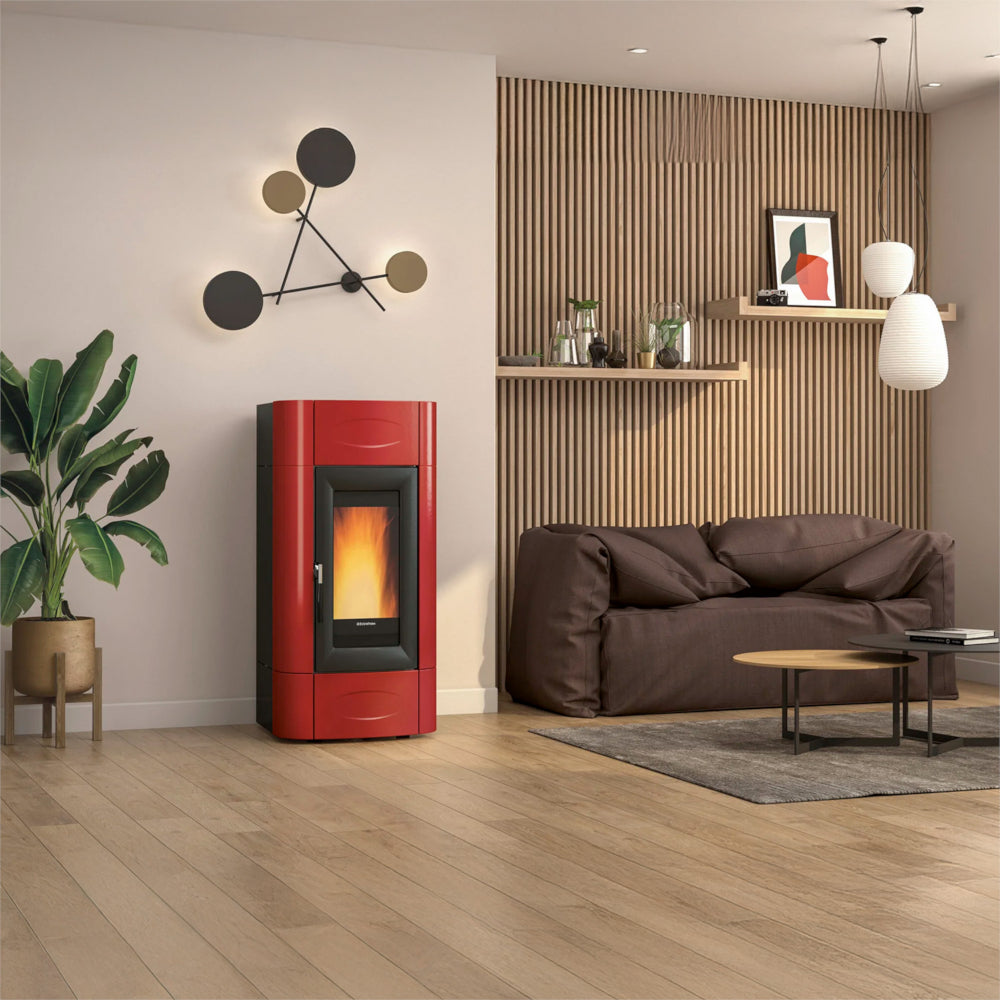 Ambientebild: Extraflame Pelletofen ISIDORA IDRO H20 5.0. EVO in Rot mit Sichtfenster, Flamme, schwarzem Rohr im hellen Wohnraum | Klimaworld.com