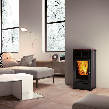 Edilkamin schwarzer, eckiger Pelletofen NARA 7 EVO mit bordeauxfarbenen Highlights in modernem Wohnzimmer mit winterlichem Fenster | Klimaworld.com