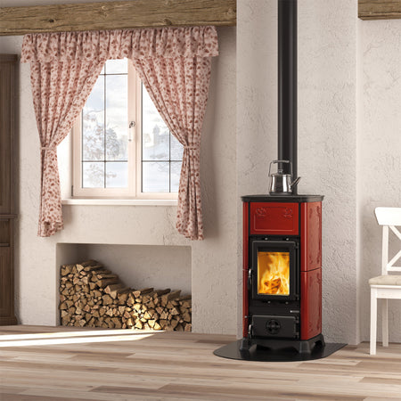 La Nordica Kaminofen EMILIANA.16 in Bordeaux mit Beispiel Flammenbild in gemuetlichem Zimmer | Klimaworld.com