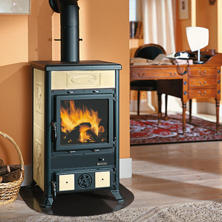 Ambientebild: La Nordica Holzofen ROSSELLA R1.16 CERAMICA, Korpus schwarz, verzierte beige Keramikseiten, Glasfenster vorn mit Feuer vor beiger Wand | Klimaworld.com
