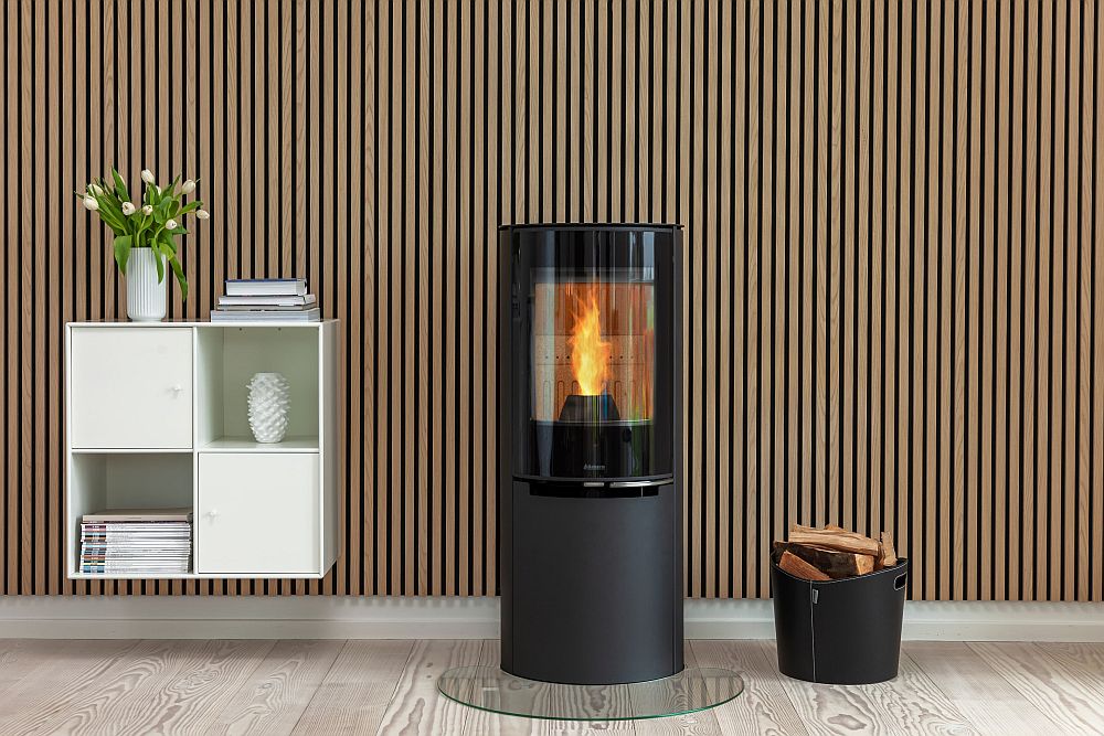 Aduro H4 Lux Hybridofen im Wohnzimmer stehend mit Funkenschutzplatte, Flamme, Holzkorb und weißem Hängeregal | Klimaworld.com