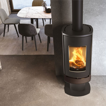 Edilkamin schwarzer Kaminofen CODE J INT mit Flammenbild, untere Verkleidung in Stahl Bronze, stehend auf Sockel in betoniertem Esszimmer | klimaworld.com