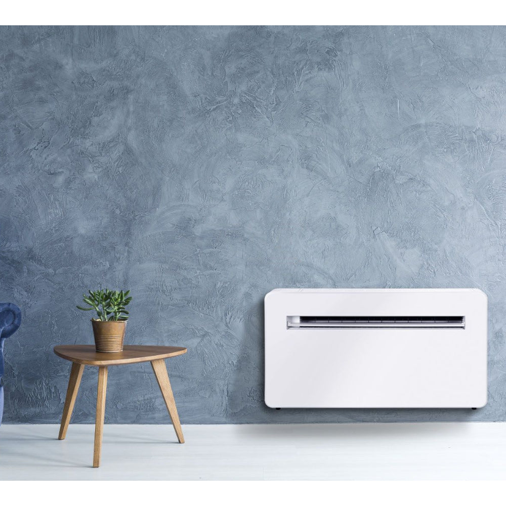 Ambientebild: MundoClima Monoblock Klimageraet MUSER-10-H12 (MC-CL20100), weisses Wandgeraet vor blauer Wand neben kleinem Holztisch mit Pflanze | Klimaworld.com
