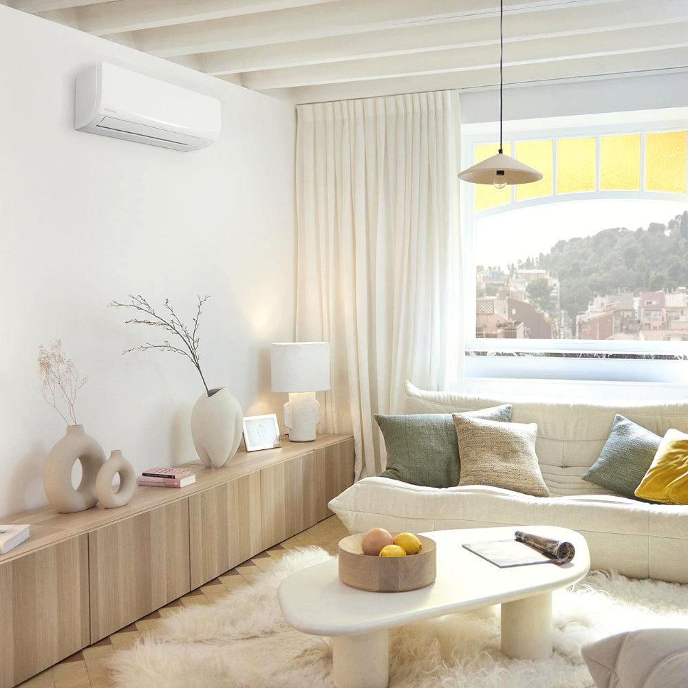 Ambientebild: Daikin FTXC-E Wandgeraet an weisser Wand, helles Wohnzimmer mit Sofa, Holzmobiliar und grossem Fenster | Klimaworld.com
