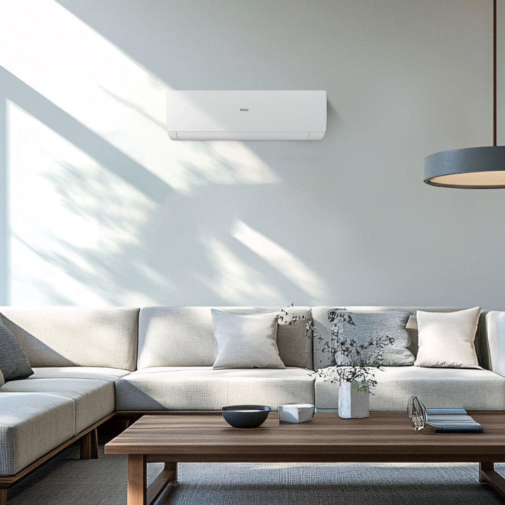 Ambientebild: Haier Klimaanlage Wandgeraet Serene an Wand ueber Sofa, Wohnzimmer mit Tisch, Kissen und Sonnenlicht Schatten | Klimaworld.com