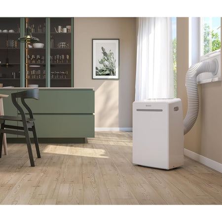 Ambientebild: OLIMPIA SPLENDID DOLCECLIMA AIRA im hellen Wohnraum mit Fenster, Schlauch und gruenem Sideboard | Klimaworld.com

