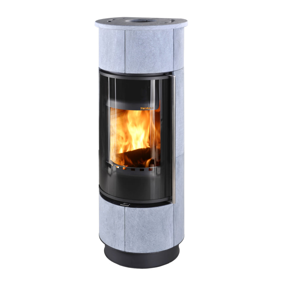 Runder Thorma Kaminofen ATIKA EXTRA mit grauer Steinverkleidung, gebogener Glasscheibe und Feuer | Klimaworld.com