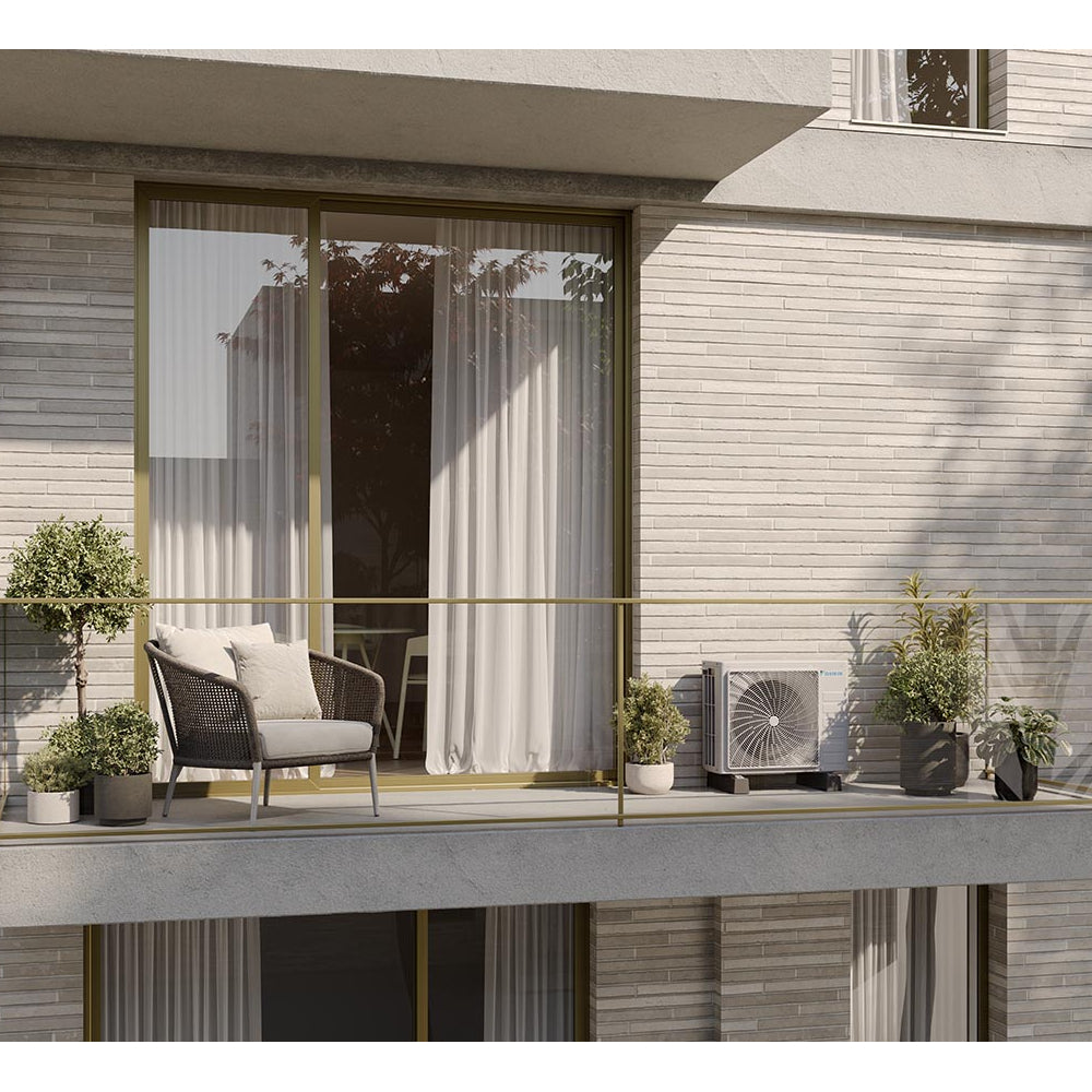 Ambientebild: Daikin Sensira Aussengeraet auf Balkon neben Pflanzen und Sessel vor grosser Glasfront mit Vorhaengen platziert | Klimaworld.com
