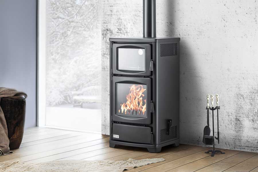 Schwarzer Teba Therm Holzofen TS-16 mit grossem Sichtfenster, brennendem Feuer und oberem Backfach in modernem Wohnraum | Klimaworld.com