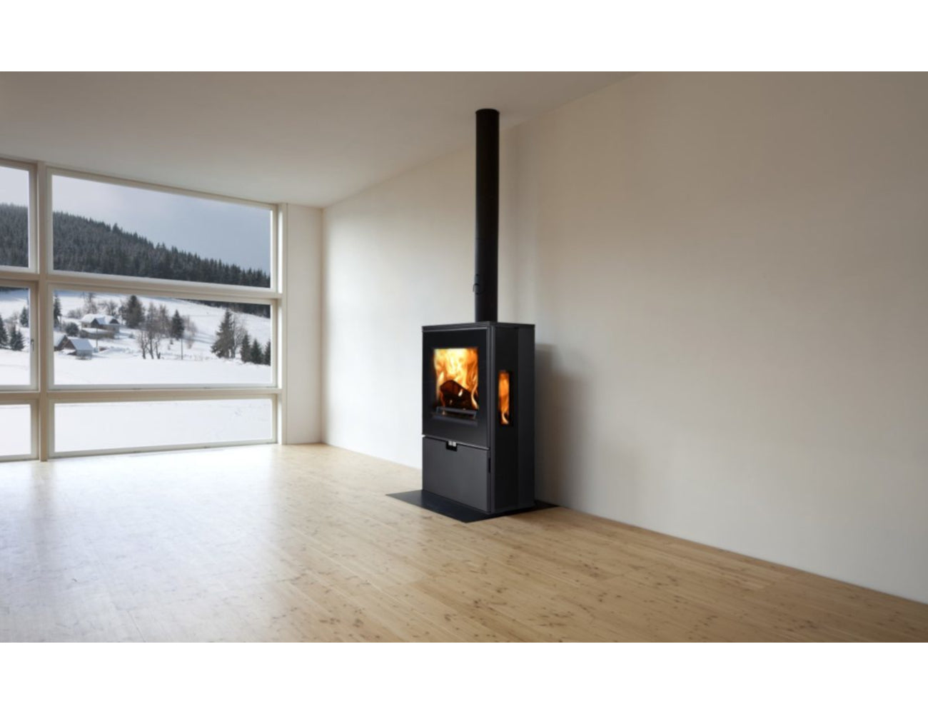 Ambientebild: Thorma Kaminofen WIESBADEN schwarz in leerem Raum mit Holzfussboden, Flamme hinter Glasscheibe, grosses Fenster | Klimaworld.com